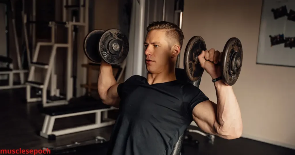 Fitness enthusiast performing dumbbell shoulder press with visible muscle engagement in deltoids.