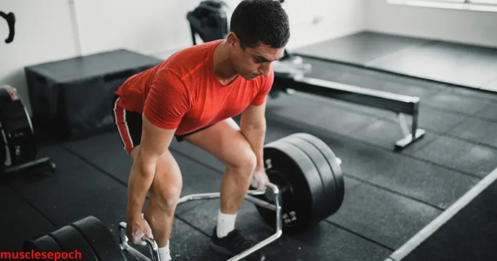 Athlete planning a strength training workout on a notepad with a trap bar and weight plates in the background.